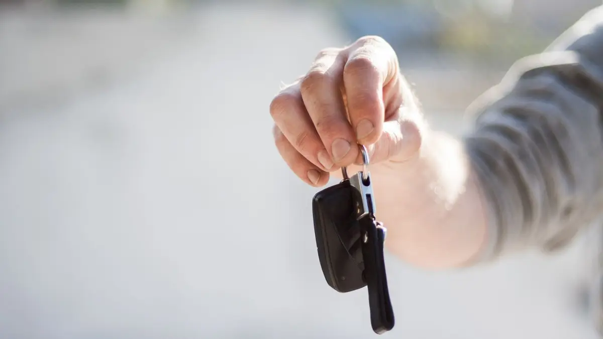 Un smartphone affichant une application de location entre particuliers devant une voiture garée en ville